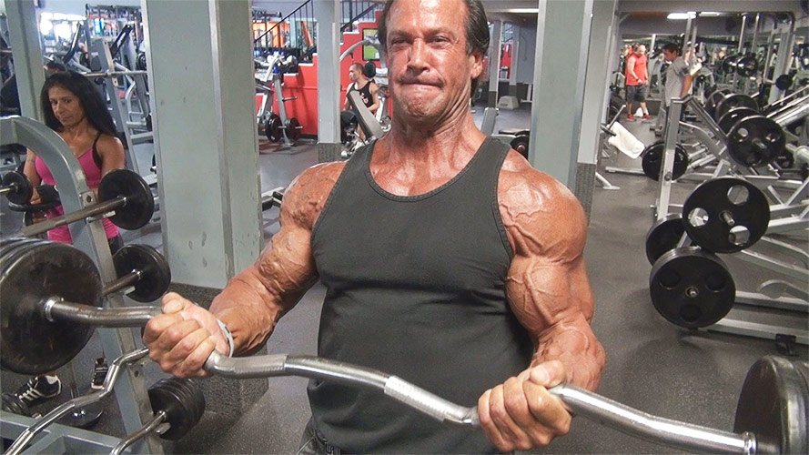 a man over 40 bicep curling in the gym
