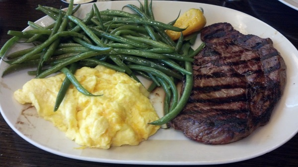 a meal consisting of steak, mashed cauliflower, and string beans