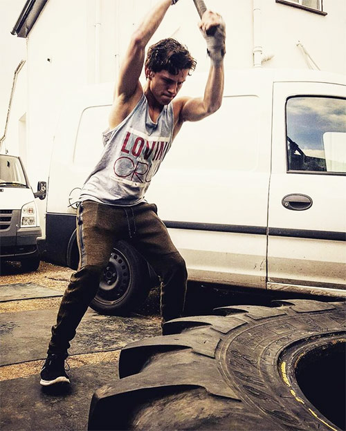 Tom Holland performing sledgehammer swings as part of his spiderman workout