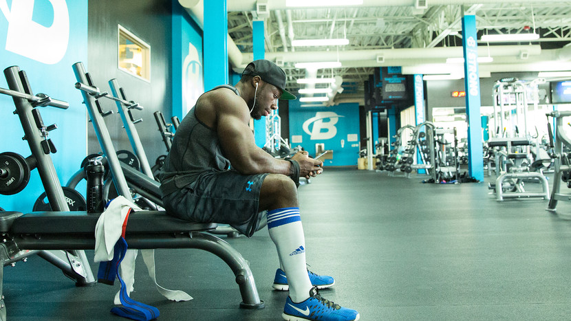 guy sitting on bench press bench texting