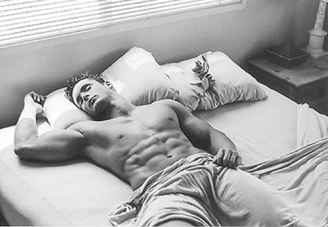a black and white image of a sleeping bodybuilder