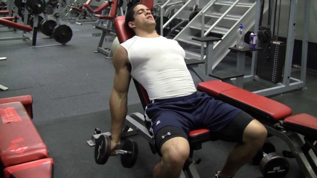 a guy performing incline curls at the gym