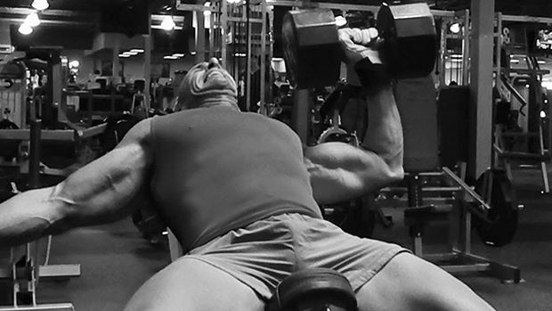 a man performing a one handed dumbbell bench press