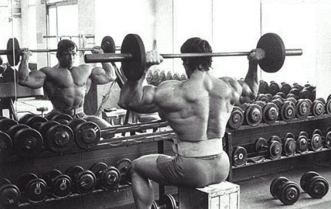 Arnold Schwarzenegger performing shoulder barbell press