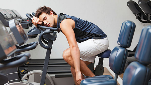 Male athlete sleeping on a bike in the gym