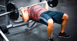 man performs close grip bench press