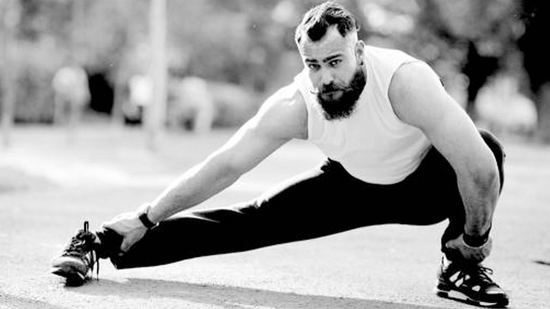 Black and white image of male athlete performing lower body mobility to improve performance