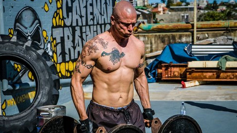 Athlete carrying two barbells as a loaded carry exercise