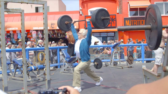 older man lifts barbell above head