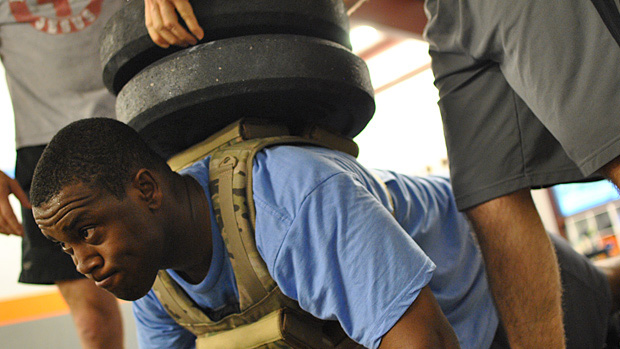 man doing weighted push ups with loaded plates on his back 