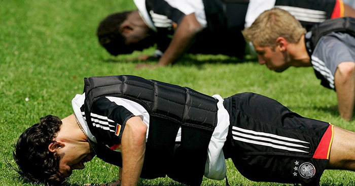 man doing group workout outside with a weighted vest for push ups 