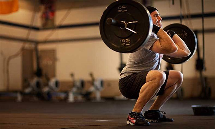 Man performs full body thrusters as part of FRAN crossfit workout