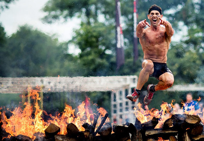 Man finishes obstacle course race by jumping over fire