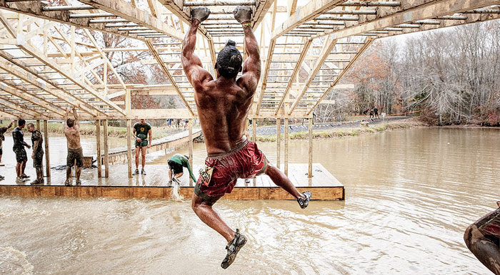 Man climbs monkey bar rigging during obstacle race