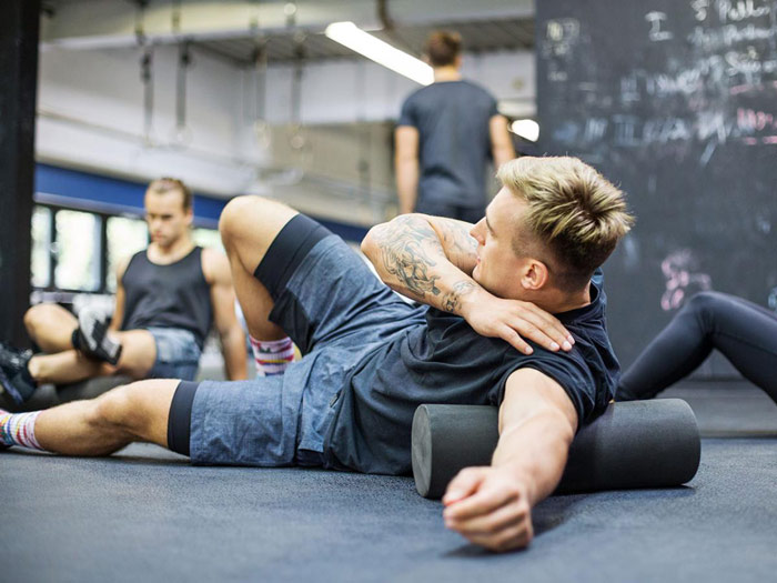 bodybuilder demonstrates foam rolling technique