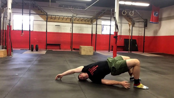 man performs supine bridge with reach