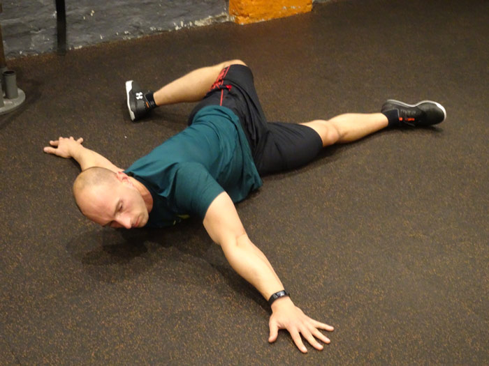 man performs scorpion stretch as mobility exercise