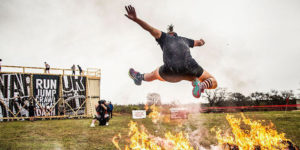 man jumps over fire during obstacle race