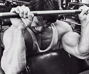 arnold schwarzenegger performing reverse pronated preacher curls for forearm and wrist training