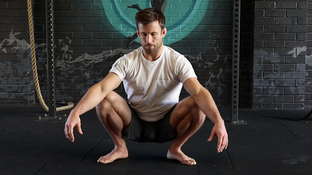 man performs third world squat in a gym