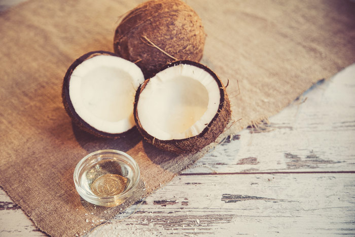 MCT oil in bowl alongside coconuts for benefits and side effects