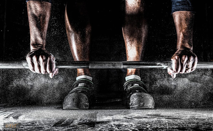 weight lifter with chalk covered hands setting up for a deadlift