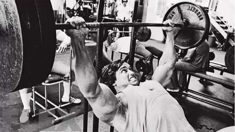 Arnold Schwarzenegger performing incline bench press to improve upper chest development