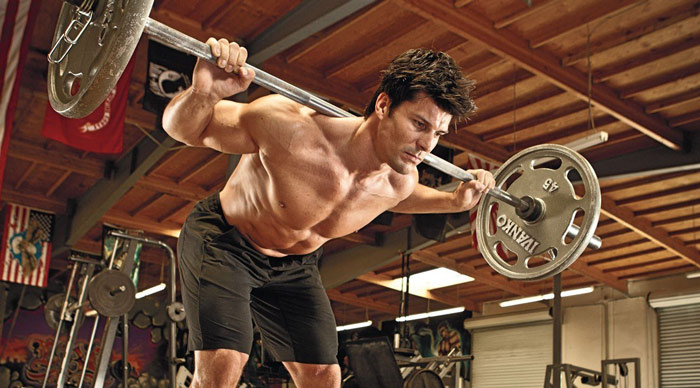 bodybuilder using a barbell good morning for hamstring and glute development