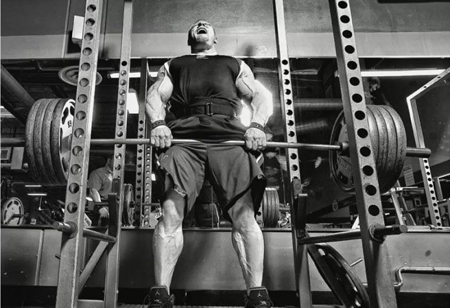 bodybuilder using power cage in home gym