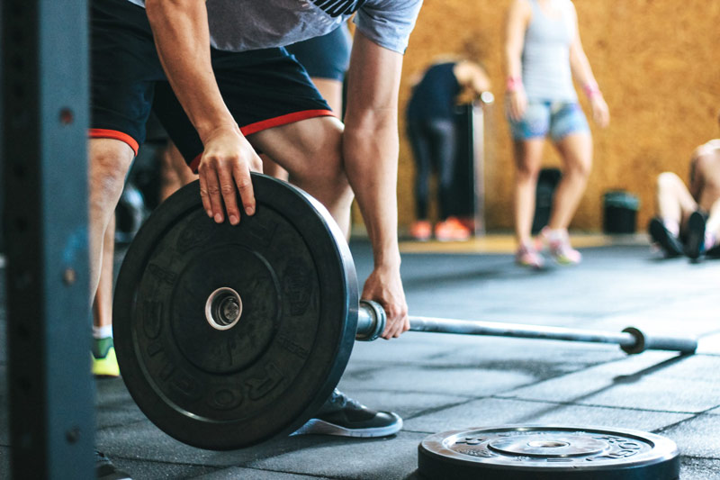 man loading barbell for strength training fat loss workout