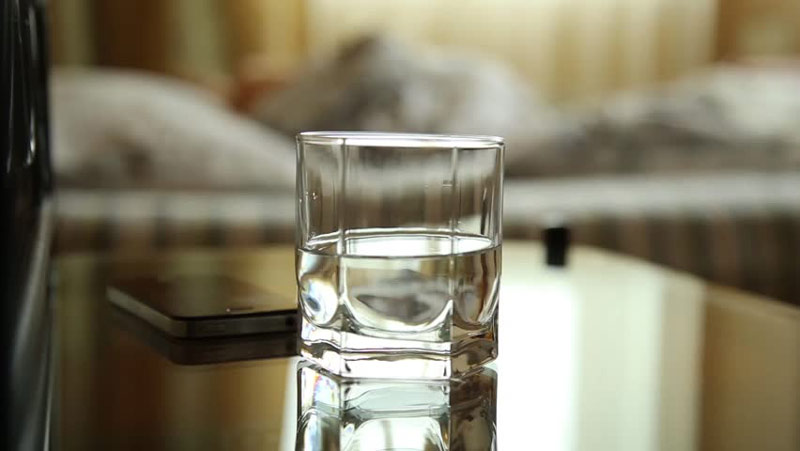 Glass of water on bedside table to be taken with AfterDrink to help prevent hangover 