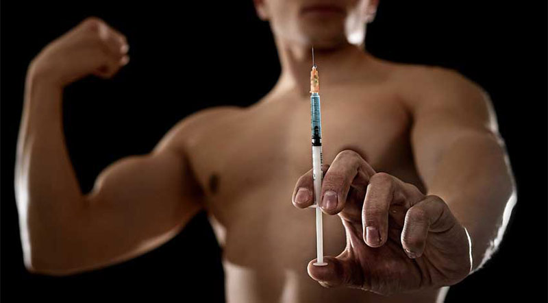 Bodybuilder holding syringe filled with synthetic testosterone