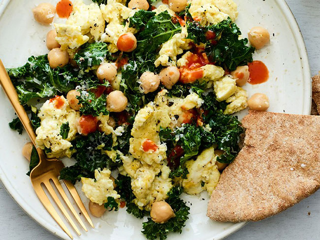 Photograph of Scrambled eggs with chickpeas kale and parmesan cheese on a plate