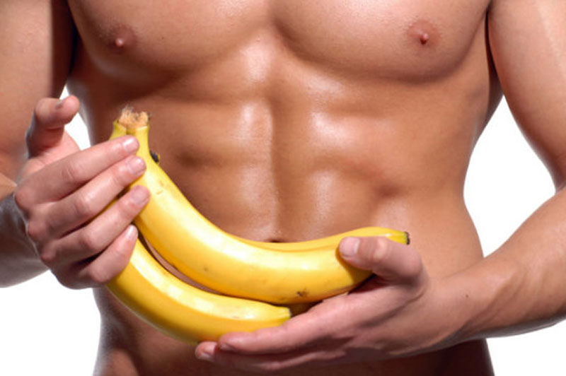 man with six pack ab muscles holding banana while carb cycling for fat loss