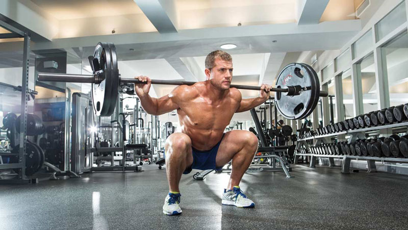 low bodyfat bodybuilder performing back squat compound lift for fat burning and six pack development