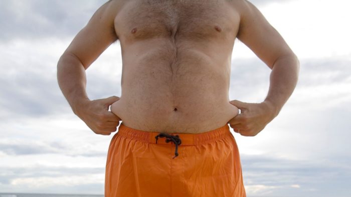man with a dad bod gripping his love handles
