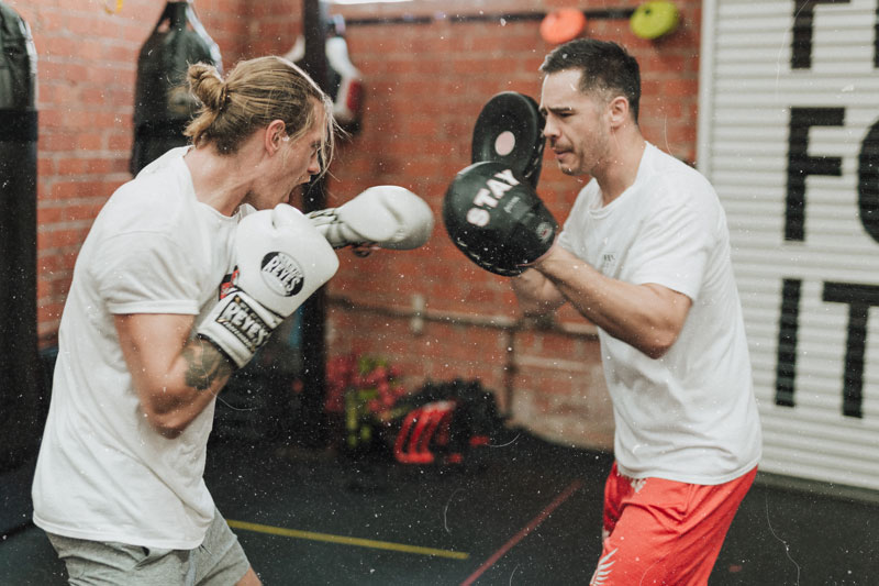 fit young male boxing with trainer