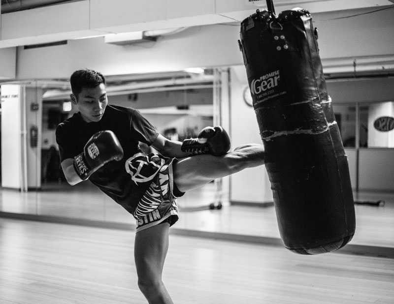 Muay Thai athlete kicking punching bag