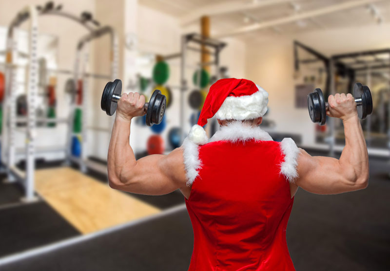 bodybuilder showing backs of biceps while dressed as santa clause