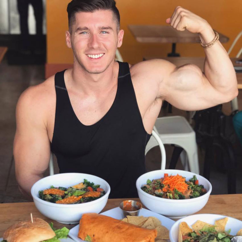vegan bodybuilder Nimai Delgado posing with high protein meal