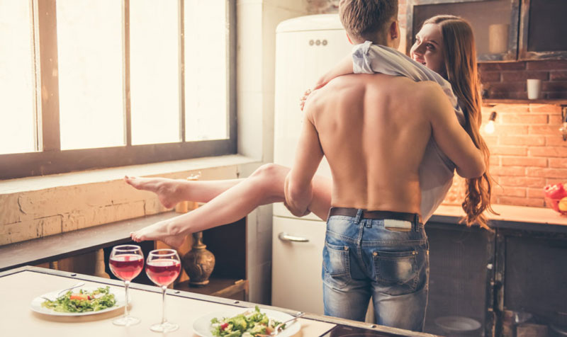 Man with healthy testosterone picking up girlfriend in front of two plates of food