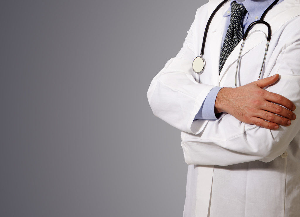 Doctor with a stethoscope at neck, grey background about to explain health effects of low testosterone