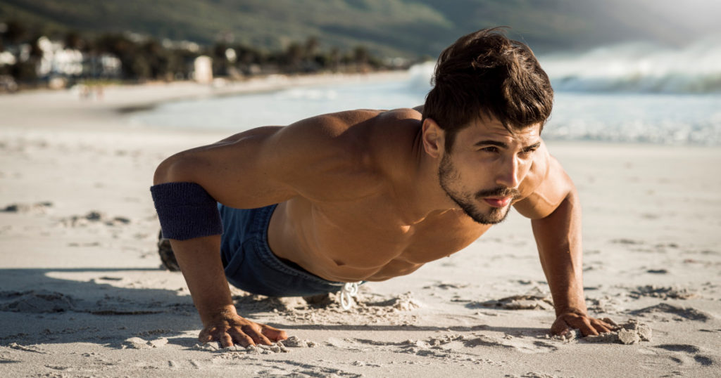 photo of a fit man doing push ups on the beach