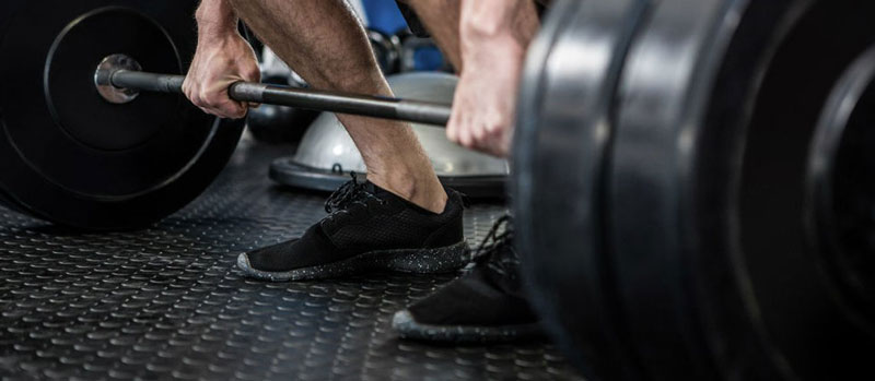 man standing over top of barbell about to deadlift it