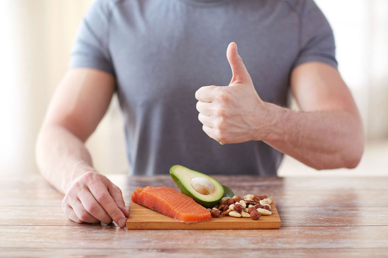 Man with thumbs up standing behind ketogenic diet foods