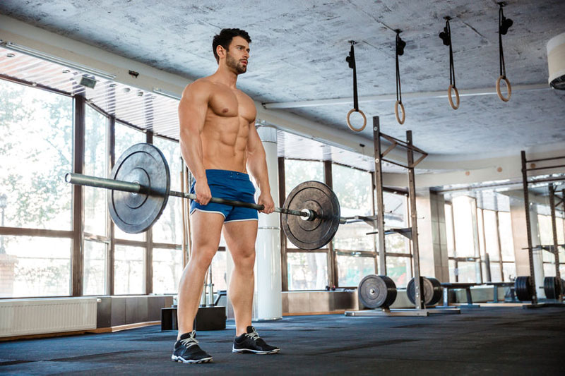 muscular man holding barbell showing signs of healthy testosterone