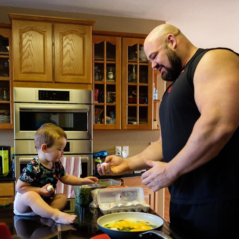 Brian Shaw cooking eggs as part of the strongman diet with his child